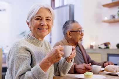 Closeup of senior woman in sweater enjoying cup of coffee 