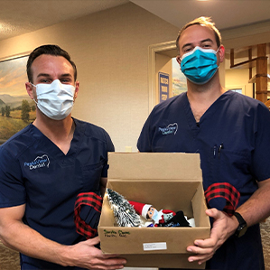 Dentists holding a box of candy from the Halloween candy buy back