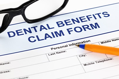 Blue top of Dental Benefits Claim Form with black-framed glasses and pen