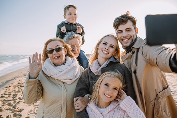 Three generations of family smiling together on a beach