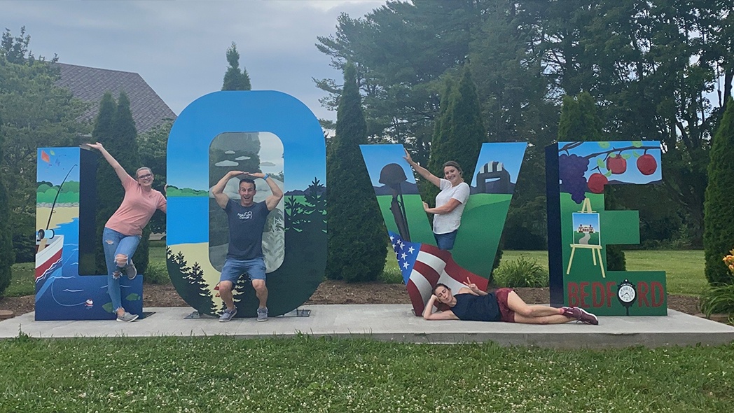 Dental team members posing in a large metal sculpture that says love