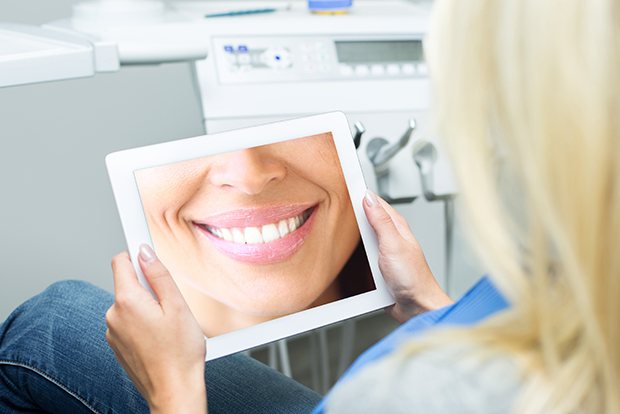 Woman looking at virtual smile design on tablet computer