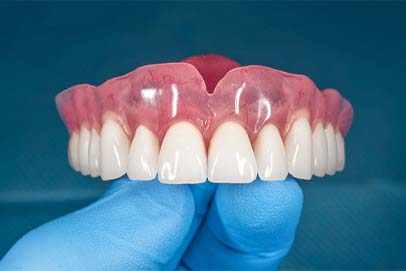 Dentist in Bedford holding full dentures