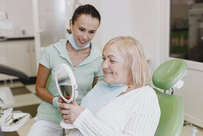 Older woman looking in mirror at dentist