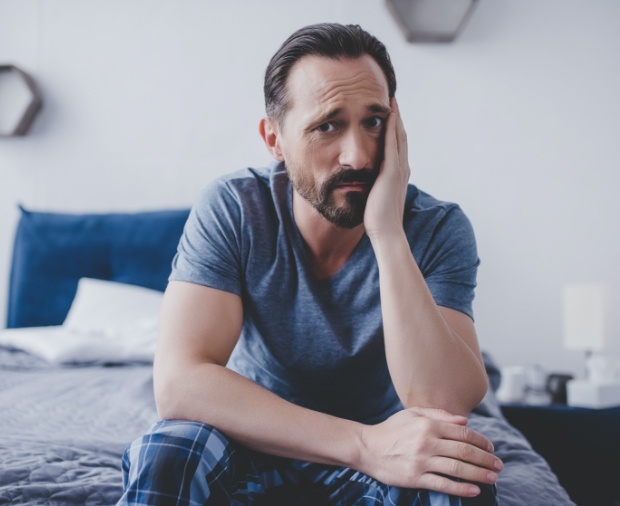 Man in need of emergency dentistry holding cheek in pain