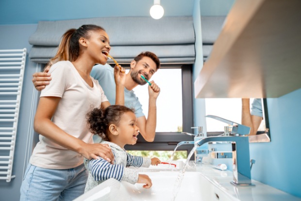 Parents and child brushing teeth together to prevent dental emergencies