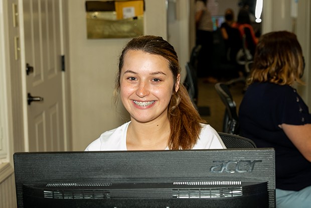 Caring dental team member smiling behind reception desk