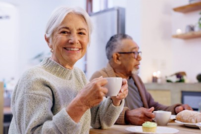 Closeup of senior woman in sweater enjoying cup of coffee