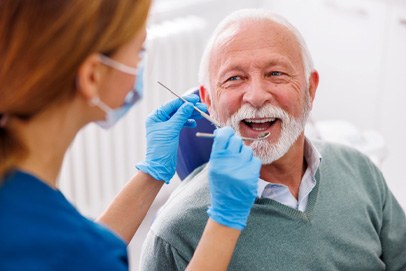 Mature man smiling at dental assistant during dental checkup  