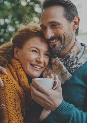 Man and woman smiling after replacing missing teeth