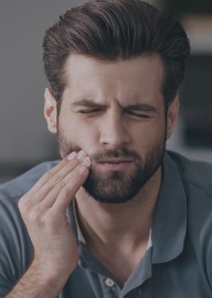 Man in need of emergency dentistry holding his cheek