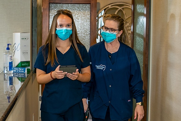 Two dental team members in dental office hallway