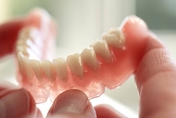 Hand holding a full denture