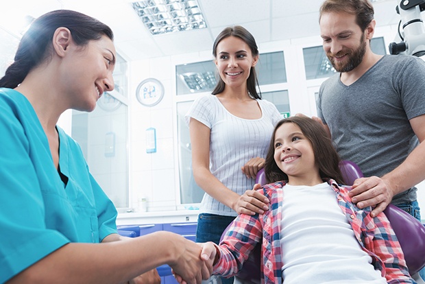 Young girl and parents talking to dentist during dental checkup and teeth cleaning