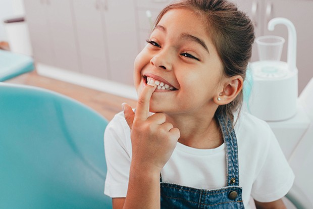 Child pointing to her smile after tooth-colored filling treatment