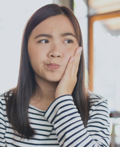 Woman in need of emergency dentistry holding cheek in pain