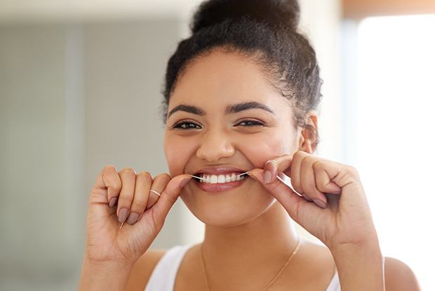 Woman flossing teeth to maintain teeth whitening results