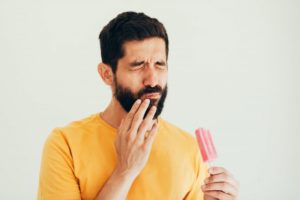 a man experiencing sensitive teeth while eating something cold