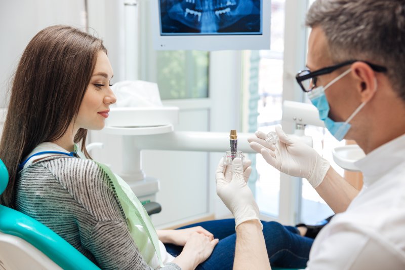 A dentist showing his patient a model of dental implants